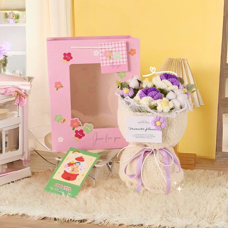 May include: A pink gift bag with a window and the text "Just for you" is next to a bouquet of purple and white crocheted flowers wrapped in a white fluffy material with a purple ribbon. The bouquet has a tag that says "Favorite flower".