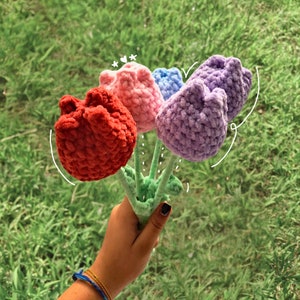 May include: A bouquet of four crocheted flowers in shades of red, pink, purple, and blue. The flowers are attached to green stems.