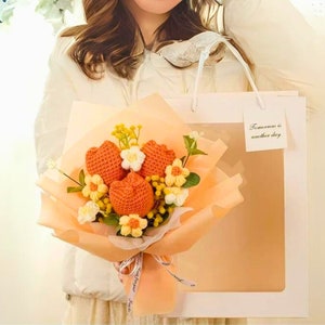 May include: A crocheted bouquet of orange tulips with white and yellow flowers in a peach-coloured gift box. The box has a clear window and a small white tag that says "Tomorrow is another day."