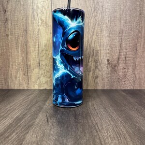 Pu&ograve; includere: Un bicchiere in acciaio inossidabile con un'illustrazione di un personaggio alieno blu. Il design presenta un personaggio con grandi occhi e denti affilati, con accenti blu elettrico e una cannuccia nera. Il bicchiere &egrave; cilindrico.