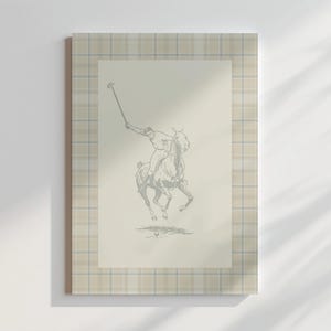 May include: A framed print with a beige and brown tartan border. The print features a black and white illustration of a person riding a horse while holding a polo mallet.