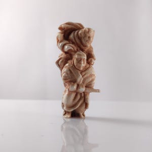 Puede incluir: Una pequeña escultura de cerámica blanca de dos figuras. Las figuras están vestidas con ropa tradicional japonesa y sostienen espadas. La escultura mide aproximadamente 10 cm de alto.