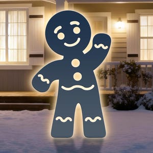 Könnte beinhalten: Eine dunkelblaue Lebkuchenmann-Dekoration mit leuchtender Kontur steht in einem verschneiten Garten vor einem Haus. Der Lebkuchenmann hat ein lächelndes Gesicht, drei runde Knöpfe und wellenförmige Linien. Das Haus hat eine Veranda und Fenster.