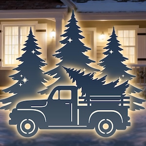Op de afbeelding: Een donkerblauwe metalen uitsparing van een vintage pick-up truck met een kerstboom, tegen een achtergrond van verlichte dennenbomen en een huis. De scène speelt zich af in een besneeuwd winterlandschap, wat een feestelijke sfeer creëert.