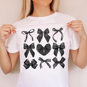 May include: A white t-shirt with a design of nine black bows in different styles.