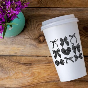 May include: A white to-go coffee cup with black and white illustrations of bows on the side.