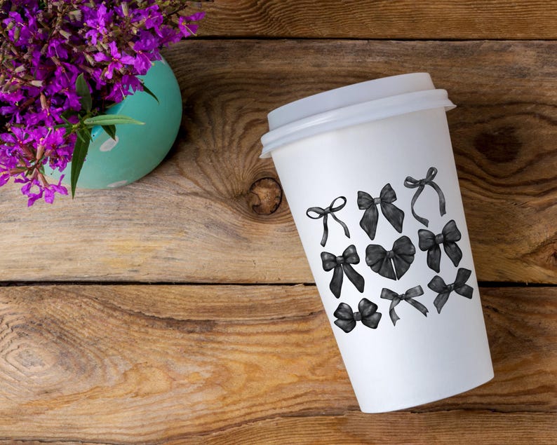 May include: A white to-go coffee cup with black and white illustrations of bows on the side.