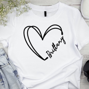 May include: White t-shirt with a black heart and the name "Brittany" written inside the heart.