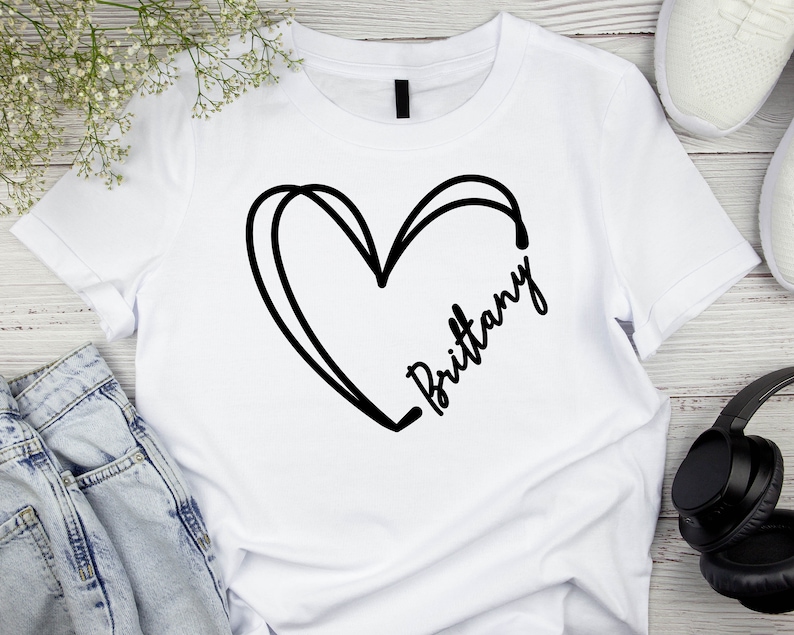 May include: White t-shirt with a black heart and the name "Brittany" written inside the heart.