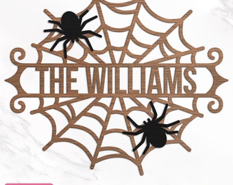 Puede incluir: Un recorte de madera de una telaraña con el texto "THE WILLIAMS" en el centro. Dos arañas negras están en la telaraña.