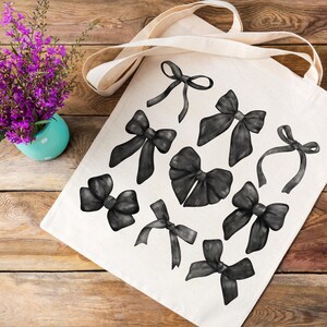May include: A white tote bag with black watercolor illustrations of bows. The bows are in various sizes and shapes, with some tied in a knot and others with loose ends.