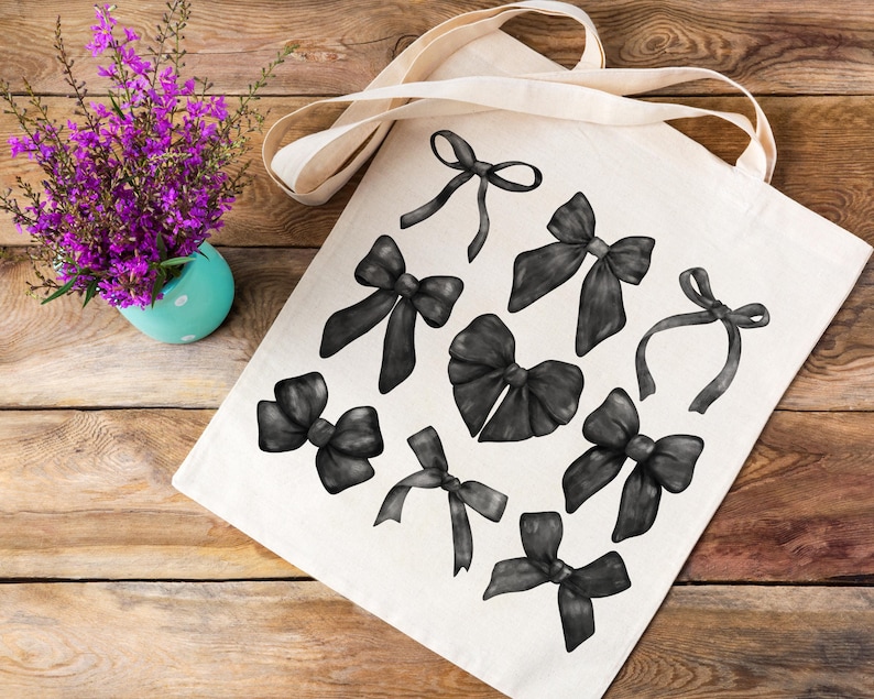May include: A white tote bag with black watercolor illustrations of bows. The bows are in various sizes and shapes, with some tied in a knot and others with loose ends.