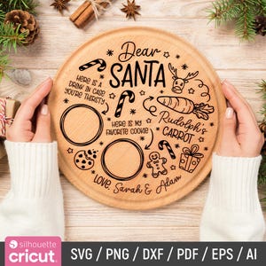Puede incluir: Una tabla redonda de madera para servir con texto grabado e ilustraciones para Papá Noel. El texto incluye "Querido Santa", "Zanahoria de Rodolfo" y "Aquí está mi galleta favorita". Hay dos recortes circulares para una bebida y galletas. La tabla está decorada con elementos temáticos navideños.