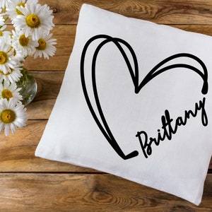 May include: White pillow with a black hand-drawn heart and the name "Brittany" written in cursive.