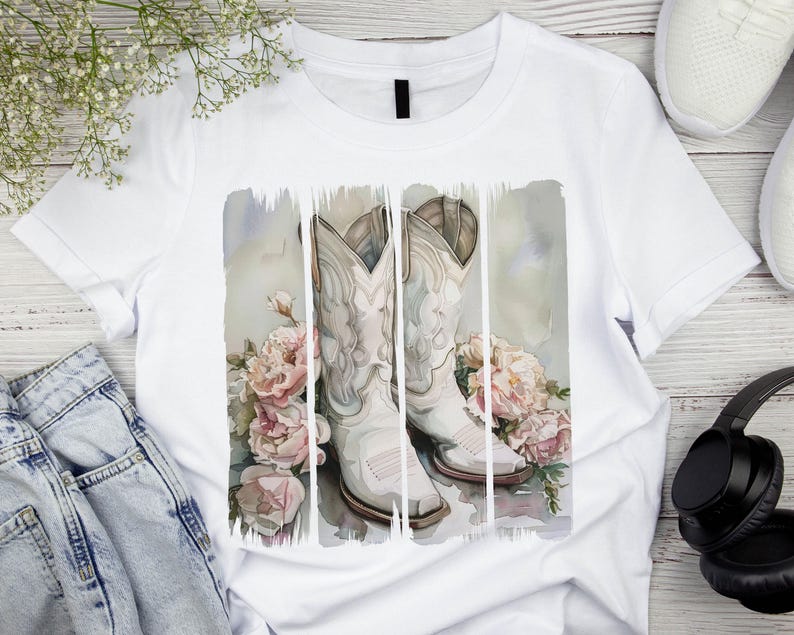 Pode incluir: Camiseta branca com um design de aquarela de duas botas de cowboy brancas com flores cor-de-rosa.