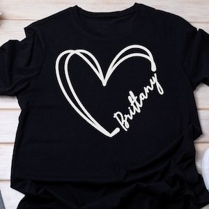 May include: Black t-shirt with a white hand-drawn heart and the name "Brittany" written inside the heart.
