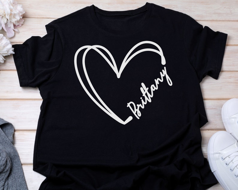 May include: Black t-shirt with a white hand-drawn heart and the name "Brittany" written inside the heart.