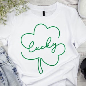 May include: White t-shirt with a green shamrock design and the word "lucky" written in a cursive font.