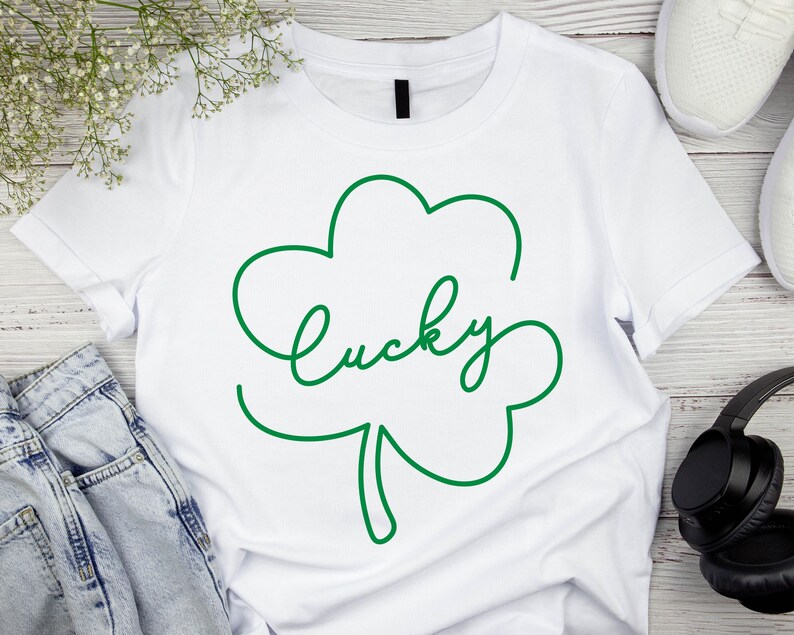 May include: White t-shirt with a green shamrock design and the word "lucky" written in a cursive font.