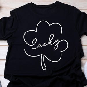May include: Black t-shirt with a white outline of a four-leaf clover and the word "lucky" written inside.