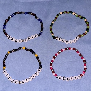 Puede incluir: Diez pulseras de cuentas de colores con diferentes nombres escritos en ellas. Los nombres son: Barrett, Zack Fair, Yuffie, Vincent Valentine, Sephiroth, Cloud Strife, Aerith, Tifa Lockhart, y dos más.