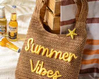May include: A brown woven straw tote bag featuring the yellow embroidered text Summer Vibes on the front and a small yellow starfish embellishment attached to the upper right side of the bag, complete with a single wide shoulder strap.