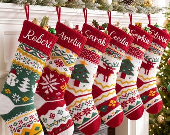 May include: Six knit Christmas stockings hanging in a row, each featuring a red cuff with a white embroidered name: Robert, Amelia, Sarah, Cecilia, Sophia, and Olivia. The stockings display festive patterns including snowmen, trees, and reindeer.
