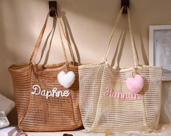 May include: Two mesh tote bags with dual shoulder straps. The left bag is tan with the white embroidered name Daphne and a white heart-shaped pom-pom. The right bag is cream with the pink embroidered name Hannah and a pink heart-shaped pom-pom.