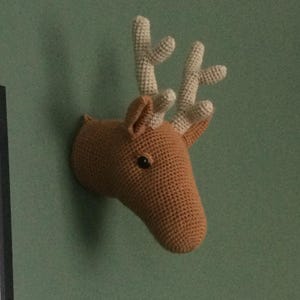 May include: A crocheted deer head wall hanging with brown fur and white antlers.