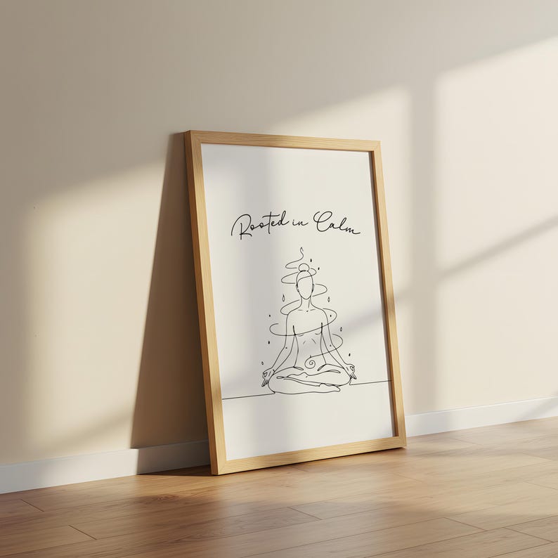 May include: A framed art print featuring a minimalist line drawing of a person in a seated yoga pose. The artwork is in black and white, with the words "Rooted in Calm" in script at the top. The frame is light brown.