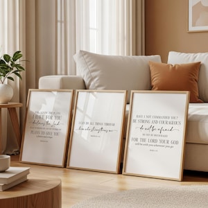 Könnte beinhalten: Drei gerahmte Kunstdrucke mit inspirierenden Zitaten in schwarzer Schrift auf weißem Hintergrund. Die Rahmen sind hellbraun. Die Drucke lehnen an einem beigen Sofa mit orangefarbenen und beigen Kissen. Der Boden ist hellbraun.