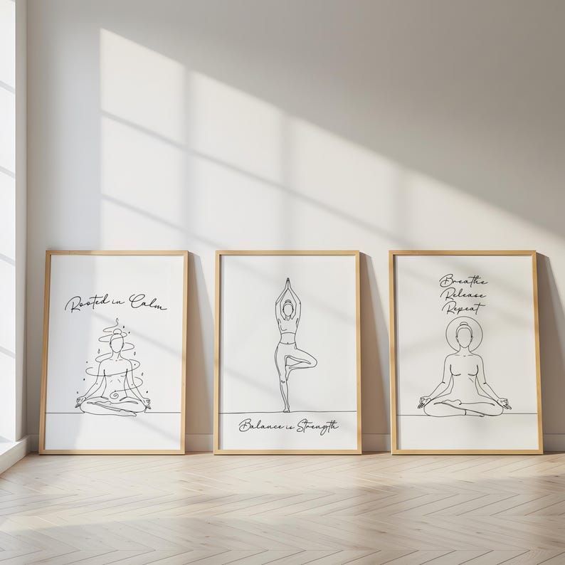 May include: Three framed art prints with line drawings of yoga poses. The prints have a white background and are in wooden frames. The first print says "Rooted in Calm", the second says "Balance is Strength", and the third says "Breathe Release Repeat".