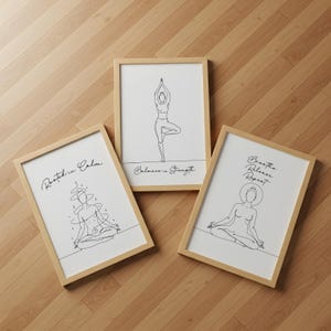 May include: Three framed art prints with line drawings of yoga poses. The prints have a light wood frame and white background. Text on the prints reads "Rooted in Calm", "Balance is Strength", and "Breathe Release Repeat".