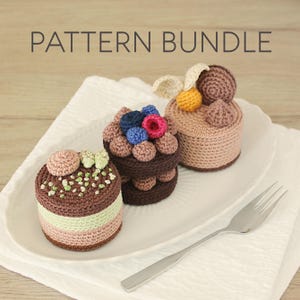 Peut inclure: Trois gâteaux crochetés avec diverses garnitures sont présentés sur un plat blanc. Les gâteaux sont bruns, roses et beiges, avec des éléments décoratifs comme des baies et de la crème. Le texte "PATTERN BUNDLE" est en haut de l'image.