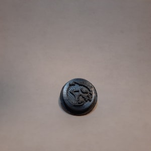 Peut inclure: Un bouton en plastique noir avec un motif de tête de loup.