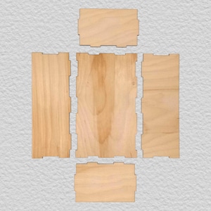 May include: A set of five flat, light-colored wooden panels with interlocking tabs along the edges. The pieces are arranged in a cross-like configuration, featuring a smooth, natural wood grain texture on each rectangular and square component.
