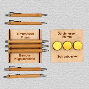 May include: A collection of bamboo ballpoint pens with silver clips and a wooden display stand labeled with 11 mm diameter. Beside it, a wooden board displays three circular yellow screw caps labeled with 28 mm diameter.