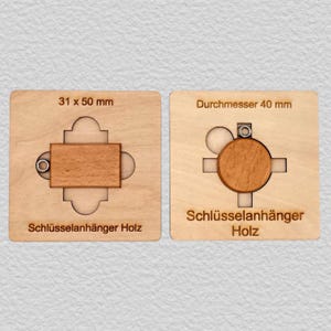 May include: Two light-colored wooden keychains set in square templates. The left rectangular piece measures 31 x 50 mm, and the right circular piece has a diameter of 40 mm. Both pieces feature a small metal ring and the text Schl&uuml;sselah&auml;nger Holz.