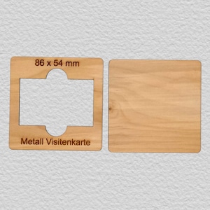May include: Two light-colored wooden rectangular templates. The left piece features a central cutout, the text 86 x 54 mm, and the text Metall Visitenkarte. The right piece is a solid, plain wooden rectangle with a visible natural wood grain pattern.