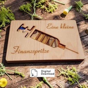 Peut inclure: Une plaque rectangulaire en bois clair avec une découpe laser en forme de seringue. À l'intérieur de la découpe, une image imprimée de billets en euros est visible. Le texte 'Eine kleine' et 'Finanzspritze' est gravé sur le bois.