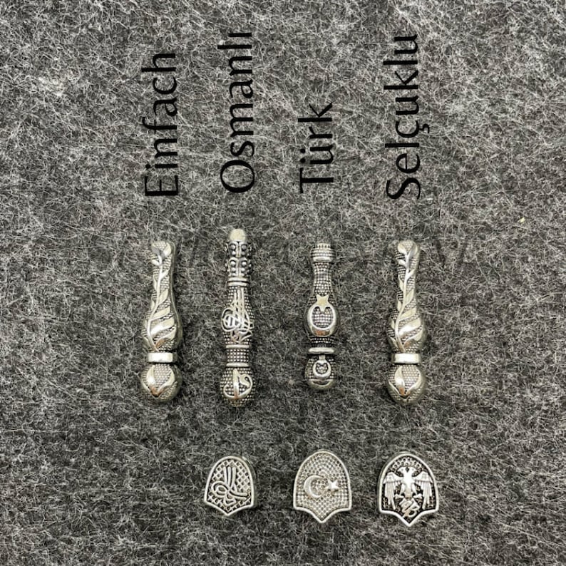 May include: Silver-toned metal pendants and charms. The pendants have ornate designs, and the charms feature emblems. The word "Einfach" is above one pendant, "Osmanlı" above another, "T&uuml;rk" above a third, and "Sel&ccedil;uklu" above the last.