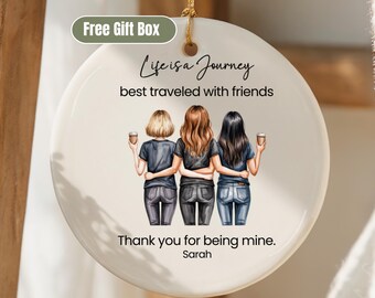 May include: A round, off-white ceramic ornament with a gold string for hanging. The ornament features an illustration of three friends with their arms around each other, holding coffee cups. Text reads "Life is a Journey best traveled with friends" and "Thank you for being mine, Sarah."