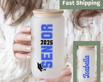May include: A frosted glass water bottle with a bamboo lid and a blue and black "Senior 2025" design. The back of the bottle is personalized with the name "Isabella".