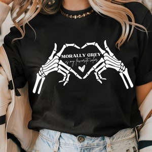 K&ouml;nnte beinhalten: Schwarzes T-Shirt mit einem wei&szlig;en Skelett-Hand-Design, das eine Herzform bildet. Der Text "Morally Grey is my favorite color" befindet sich im Herzen.