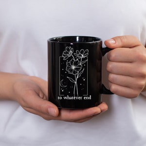 May include: Black ceramic mug with a white floral design and the text "to whatever end".