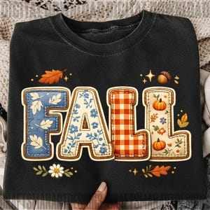 May include: A black crewneck t-shirt featuring the word FALL in large, block-style letters. Each letter has a unique pattern: blue with white leaves, blue floral, orange and white gingham check, and cream with pumpkins and autumn foliage.