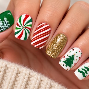 May include: Manicured fingernails featuring festive holiday nail art designs. The nails display a variety of patterns including white pine trees on a green base, red and green swirls, red and white stripes, gold glitter, and green trees on white.
