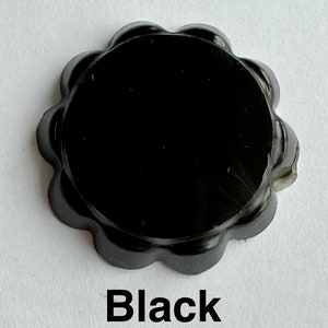 Puede incluir: Un sello de cera redondo negro con bordes festoneados y la palabra "Negro" impresa debajo.