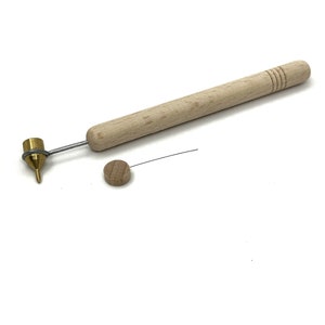 以下が含まれることがあります： 真鍮の先端と小さな木製の円盤が付いた木製の道具。この道具は、クラフトや創作に使用されます。