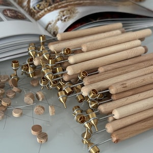 Puede incluir: Primer plano de un montón de herramientas de madera con puntas de latón. Las herramientas se utilizan para la pintura de puntos y están dispuestas en un patrón aleatorio.